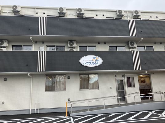 ハウスマイルの表示がある白い外壁の3階建て住宅