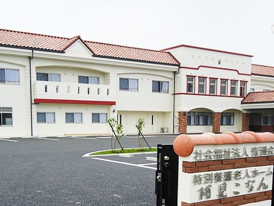 2階建ての建物は白い外壁に赤いラインが入っていて、屋根もエンジ系の色。広い駐車場もある。