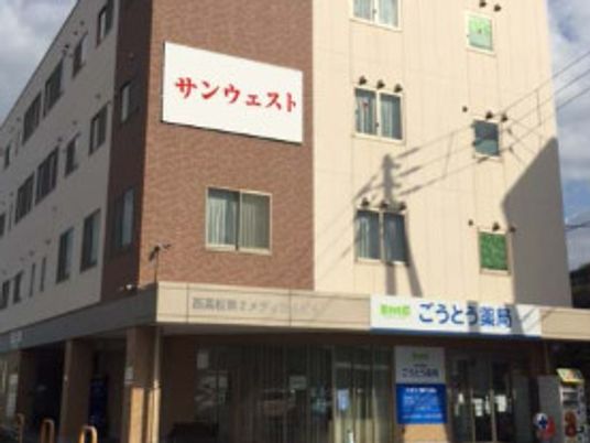 ベージュとブラウンの4階建ての建物の玄関には車寄せが付き、日当たりのいい場所に建っている。