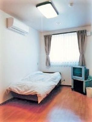 ワンルームの部屋にベッドやテレビ、エアコン、照明がある様子が写っている