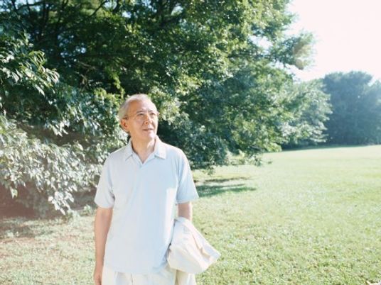 広大な緑が広がる公園内で散歩している高齢者。敵が良い日の散歩の様子