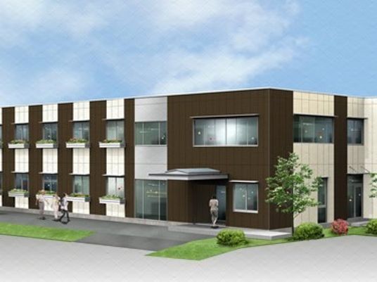 ２階建ての建物。白とブラウンの落ち着いた雰囲気で周辺には木が植えられている。