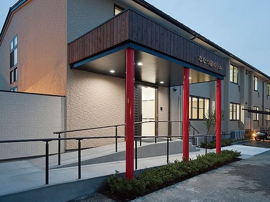 車いす用のスロープがついた施設のエントランス付近。赤い柱が印象的なスペース