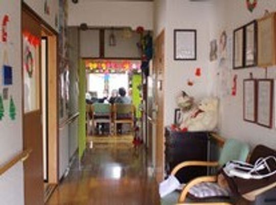 手すりが付いた廊下にはいすやぬいぐるみが置かれ、壁には手すりが付いている。手作りの装飾品が飾られている。
