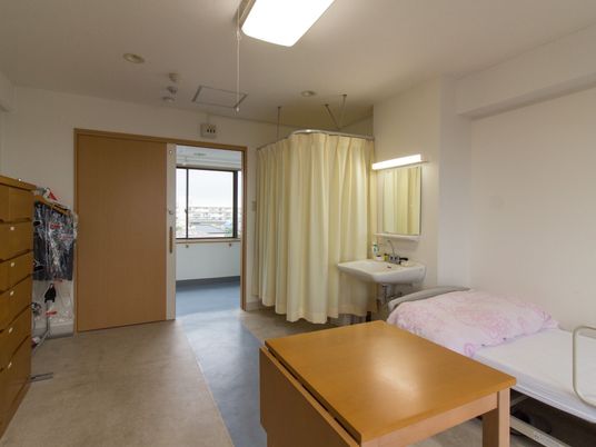 トイレはカーテンで囲われ、ベッドには寝具がセットされ、洗面所やテーブル、タンスなどがある。