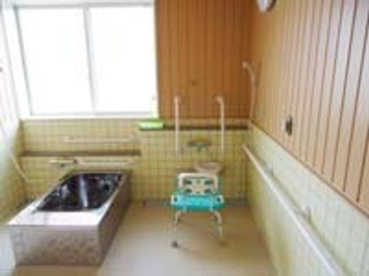 大きな窓が付いた明るい雰囲気の浴室には一人用の浴槽が設置され、３方向から介助が可能。シャワーチェアも置かれている。