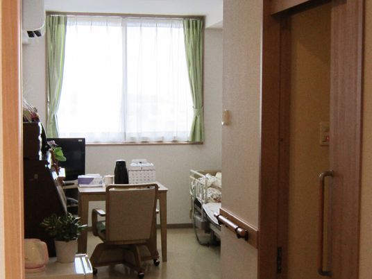 居室には寝具付きのベッドやテレビ、デスクセットがあり、トイレにはスライド式のドアが設置されている。
