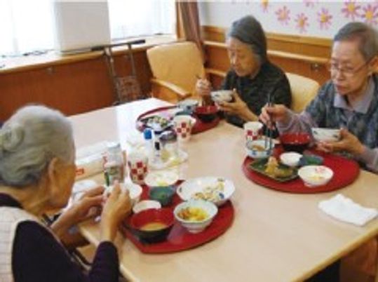 おやつを食べている高齢者の様子。施設内の食事の風景を写した写真