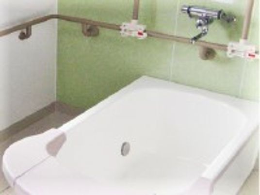 白い浴槽はゆったりとしたデザイン。壁には手すりが付いている。