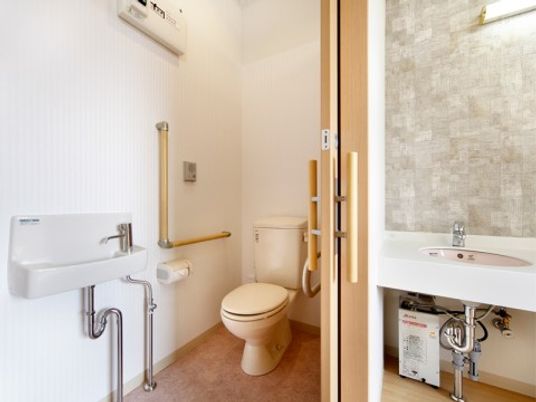 車イスでも楽に利用できる居室トイレの様子です。手すりや洗面など使いやすさに配慮した設計です。