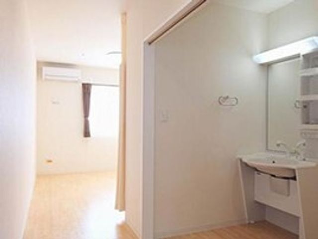 手前に洗面台がついている施設内の居室の様子。ワンルームタイプの部屋 お部屋に充実設備があるので、施設でも快適に過ごせます。オールバリアフリー・手すり完備の安全性も魅力です。