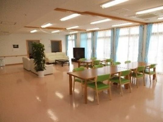 リビングダイニングには大きな窓があり、木製のダイニングテーブルが複数置かれ、テレビやソファがある。