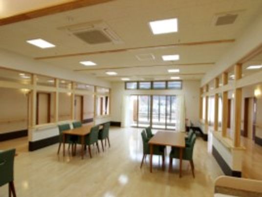 グリーンの椅子とベージュの机の組み合わせが複数ある広い空間