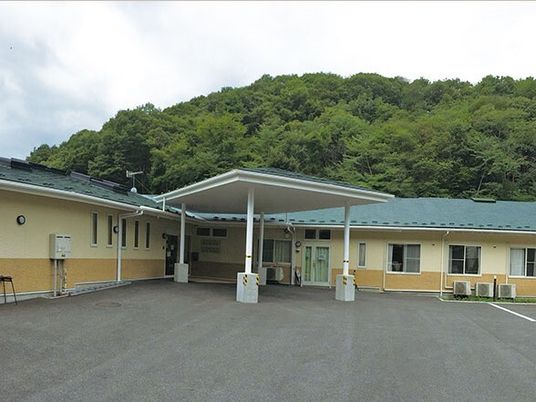 平屋建ての建物にはグリーンの屋根が付き、広い駐車場もある。緑豊かな環境。