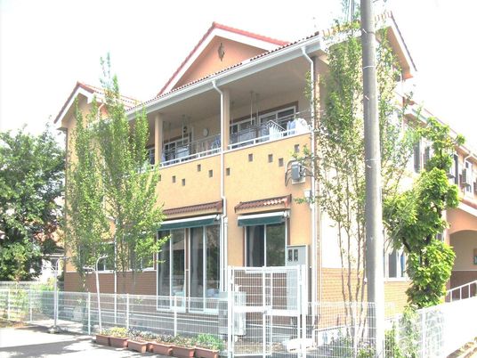 ２階建ての建物は一般の住宅のような雰囲気。２階にはベランダが付き、周辺には緑が多い。