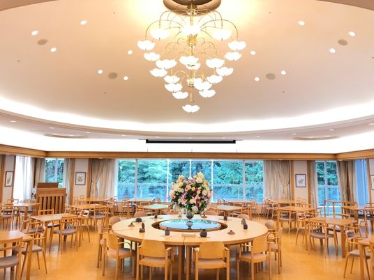 医師・看護師と笑顔で話している高齢者女性。車いすに乗っている様子