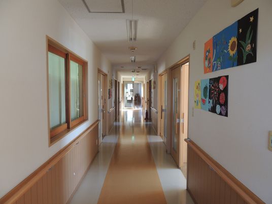 壁に絵画が飾られており、手すりがついている長い廊下