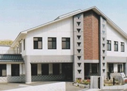 三角屋根の建物は白壁に瓦屋根で和の雰囲気が漂う。周辺には自然も多い。