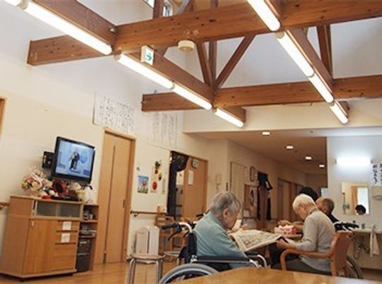 ハリが見える民家風デザインの施設内のリビング。高齢者が集まってくつろいでいる様子