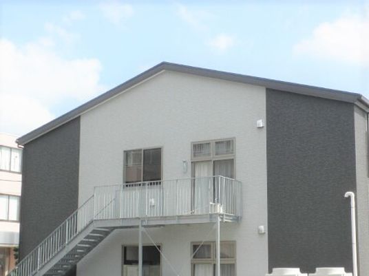 ２階建ての建物の外には避難用の階段がある。敷地内には駐車スペースもある。