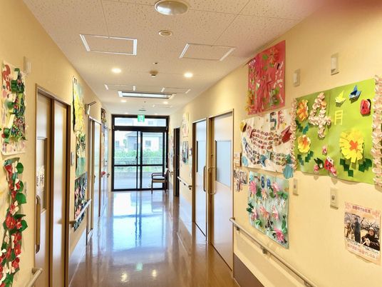 まっすぐな廊下の両サイドの壁には手すりが設置され、たくさんの創作作品が飾られ、突き当りにはいすが置かれている。