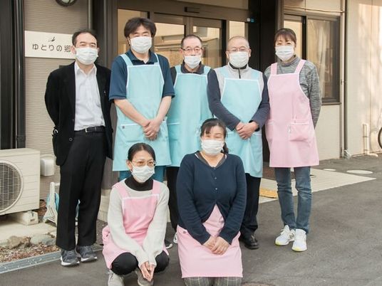 ピンクやグリーンのエプロンを付けた男性スタッフと女性スタッフが集合している。