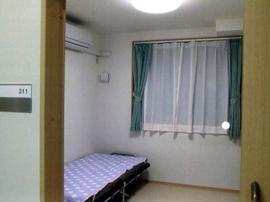 一人用の部屋を写した写真。　絵加温、ベッド、収納、窓が写っている