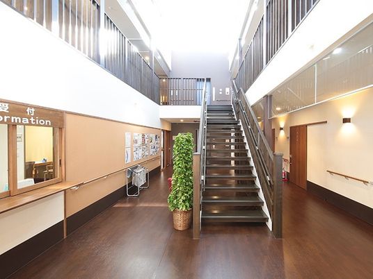 施設の吹き抜け・階段部分の写真。手前にスタッフステーションがある様子