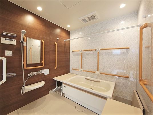 三方向の壁に手すりがついている施設内の個別浴室の様子。腰かけようのスペースがある浴槽