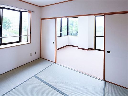 和室と洋室がつながっていて、明るい雰囲気の居室。窓が多く家具などは置かれていない。