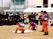 高校の運動場で防災訓練。オレンジ色の服を着た消防団の実演を高校生と入居者が見守っている。