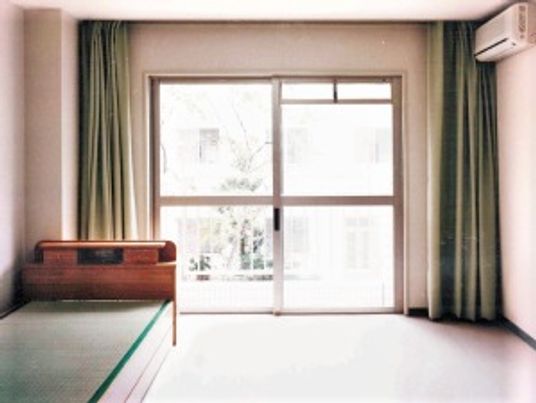 カーテン付きの窓がある部屋の様子。エアコンとベッドが置いてある部屋