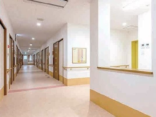 両側に個室のドアが写っている施設内の共有スペースの様子。広めの廊下の様子がわかる