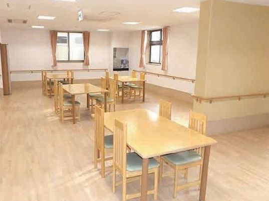 四人掛けのテーブルと椅子が並ぶ小さめのリビング。手すりがついた壁が見えている写真