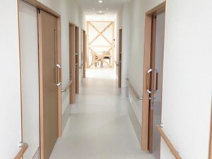施設内の廊下を写したもの。両側に個室に入るドアがあるのがわかる
