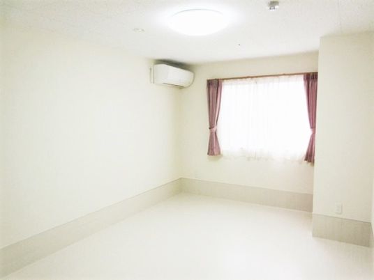 奥のほうに窓がある広めの個室の様子。エアコンとカーテンがかかった窓が移っている写真