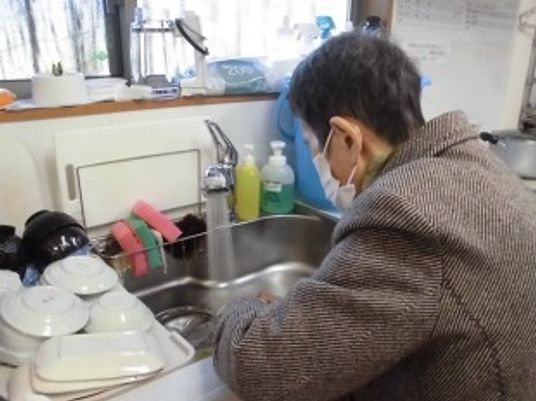 食器を洗っている高齢者の様子。施設内で家事をしている入居者