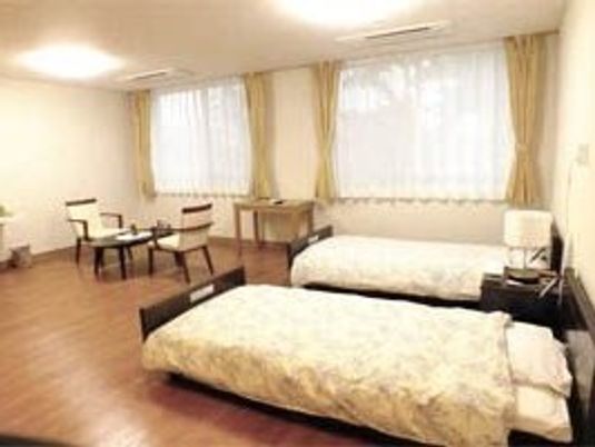 ベッドが2つとリビングセットが置いてある施設内の二人部屋の様子