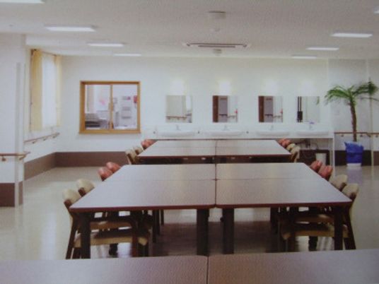 大きなダイニングテーブルセットが複数置かれた広い共有スペース。たくさんの洗面所もある。