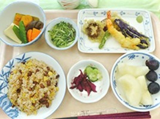 ごはんとおかず類、フルーツがお盆に並べられている施設の食事メニュー