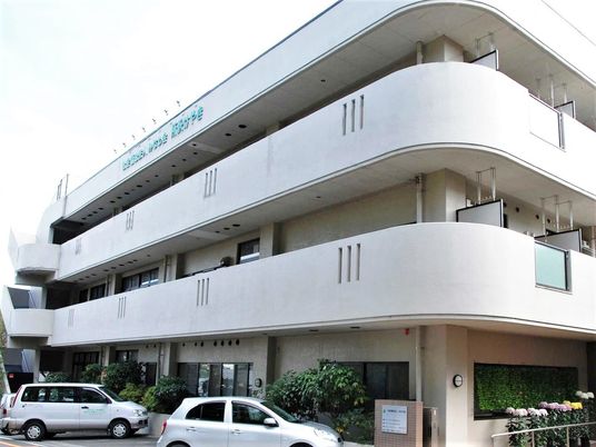3階建ての建物は白を基調としていて、ベランダが各フロアにつき、屋外階段も設置されている。