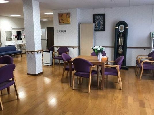 四人掛けのテーブルと椅子が置かれている施設内の食堂、共有スペースの様子
