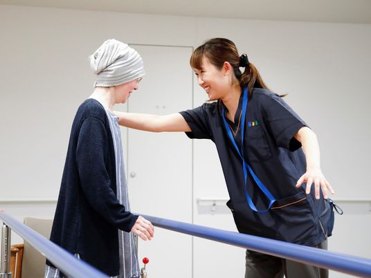 リハビリをする利用者の体を支えながらほほえむスタッフ