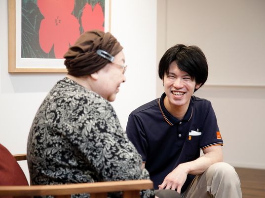 椅子に座った女性入居者と会話をする男性スタッフ