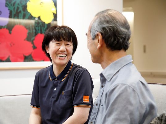 男性入居者と目を合わせてほほ笑むスタッフ