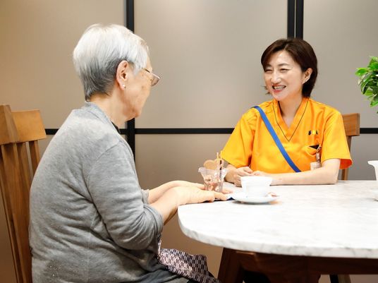 ティータイムを楽しみながらスタッフと会話をする女性入居者の様子
