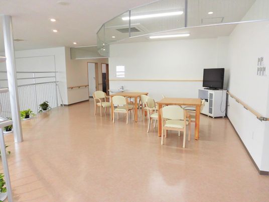 テレビが置いてある施設内の共有スペース。椅子とテーブルが並んでいるところ