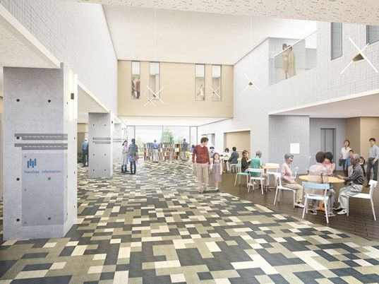 1階部分の共有スペースでは、地域の人々が集まりにぎやかな雰囲気。テーブルセットが複数並び、ライブラリーもある。