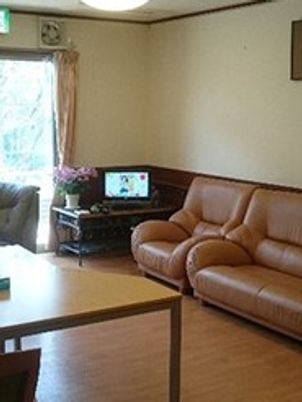 テレビやソファが置かれたフローリングのリビングには花が飾られている。大きなダイニングテーブルもある。