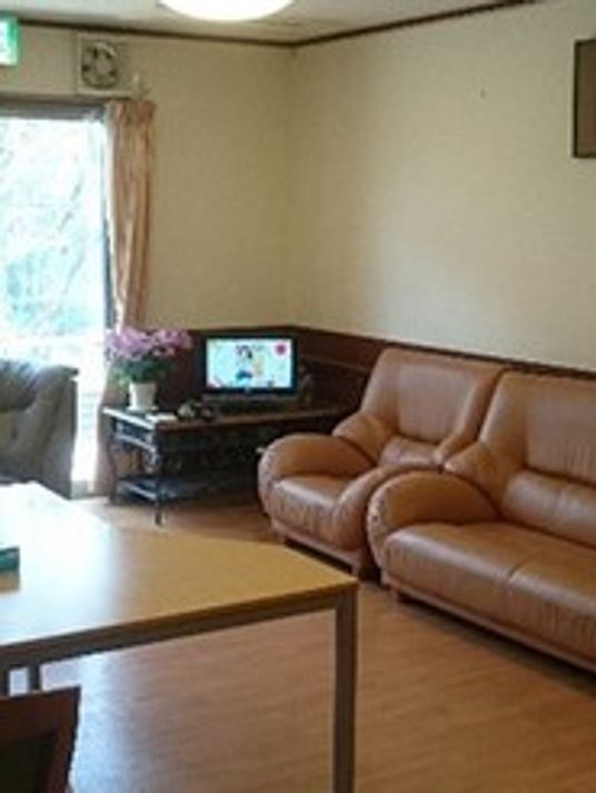 テレビやソファが置かれたフローリングのリビングには花が飾られている。大きなダイニングテーブルもある。